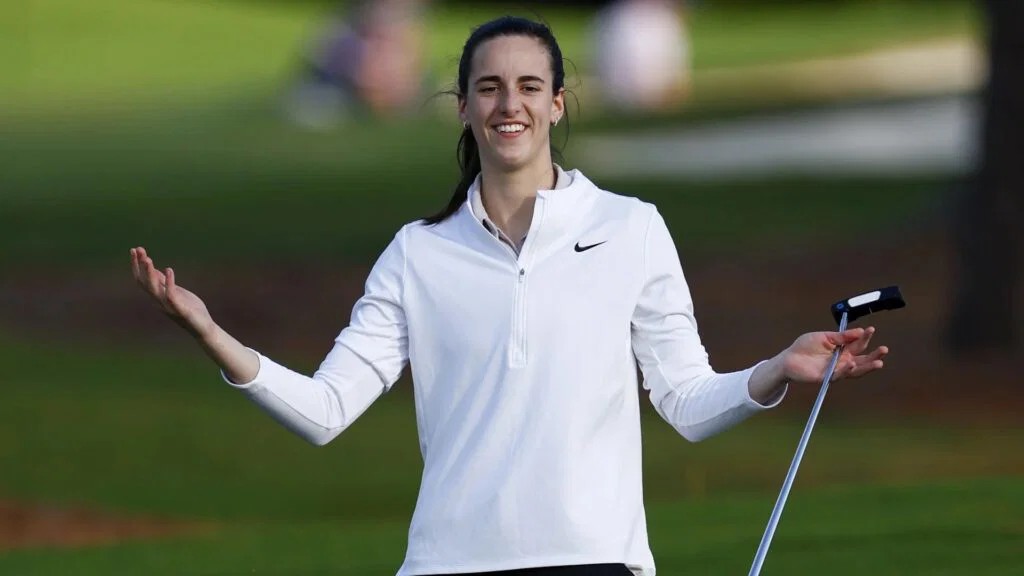 Caitlin Clark smiling with a putter on a golf course during a pro-am round